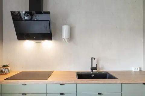 Kombinasjonen av den flate induksjonstoppen, det stilige armaturet og den moderne ventilatoren gir kjøkkenet et skikkelig eksklusivt løft. Legg merke til de stilige baderomsplatene/veggen i betonglook – superenkelt å holde rent etter kokkeleringen!