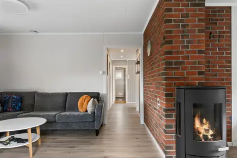 Stuen oppleves som lys, åpen og luftig, med et flott gulv som binder rommene sammen. Den tøffe murveggen og peisen blir det naturlige blikkfanget og sørger for både lun varme og en skikkelig koselig atmosfære.
