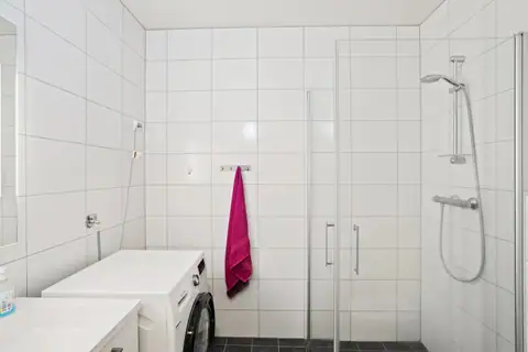 An inviting and bright bathroom accessed directly from the hallway. The bathroom is practically fitted out with modern tiles on walls and floor and a spacious shower area with folding glass screens.
