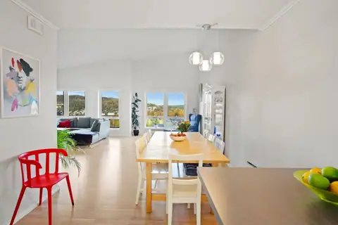 An inviting dining area strategically placed between kitchen and living room. The impressive ceiling height and light surfaces create a lovely setting for meals, while the large windows in the background ensure a great view!
