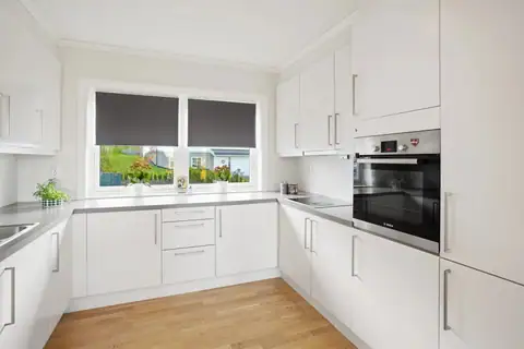 The kitchen is bright and inviting, with neutral colours and a grey worktop that harmonises well with the floor. The units reach up towards the ceiling for maximum use of space.