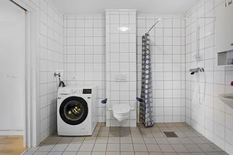 Flislagt bad med vegghengt wc, dusjhjørne med forheng, servant med speil og overskap. Opplegg for oppvaskmaskin.