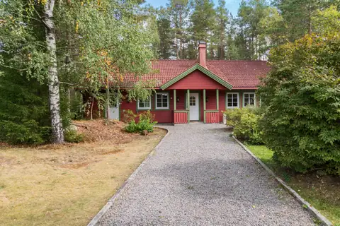 Idyllisk eiendom meg gruset innkjørsel og ryddig grense med kantstein mot gresset.