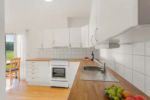 Kitchen with flat white doors and a water heater in the base unit. The appliances included are a brand-new dishwasher (used only 4 times), a cooker and a combined fridge-freezer.